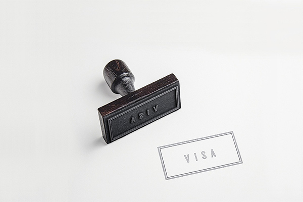 Rubber stamp showing the word VISA lies diagonally on a white surface, next to its clear imprint.