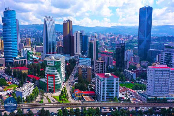 A vibrant Addis Ababa cityscape with diverse skyscrapers under a partly cloudy sky. The buildings vary in shape and size.