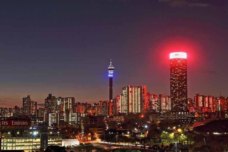 Vibrant night skyline and city lights. Book flights to Johannesburg for an urban South African adventure.